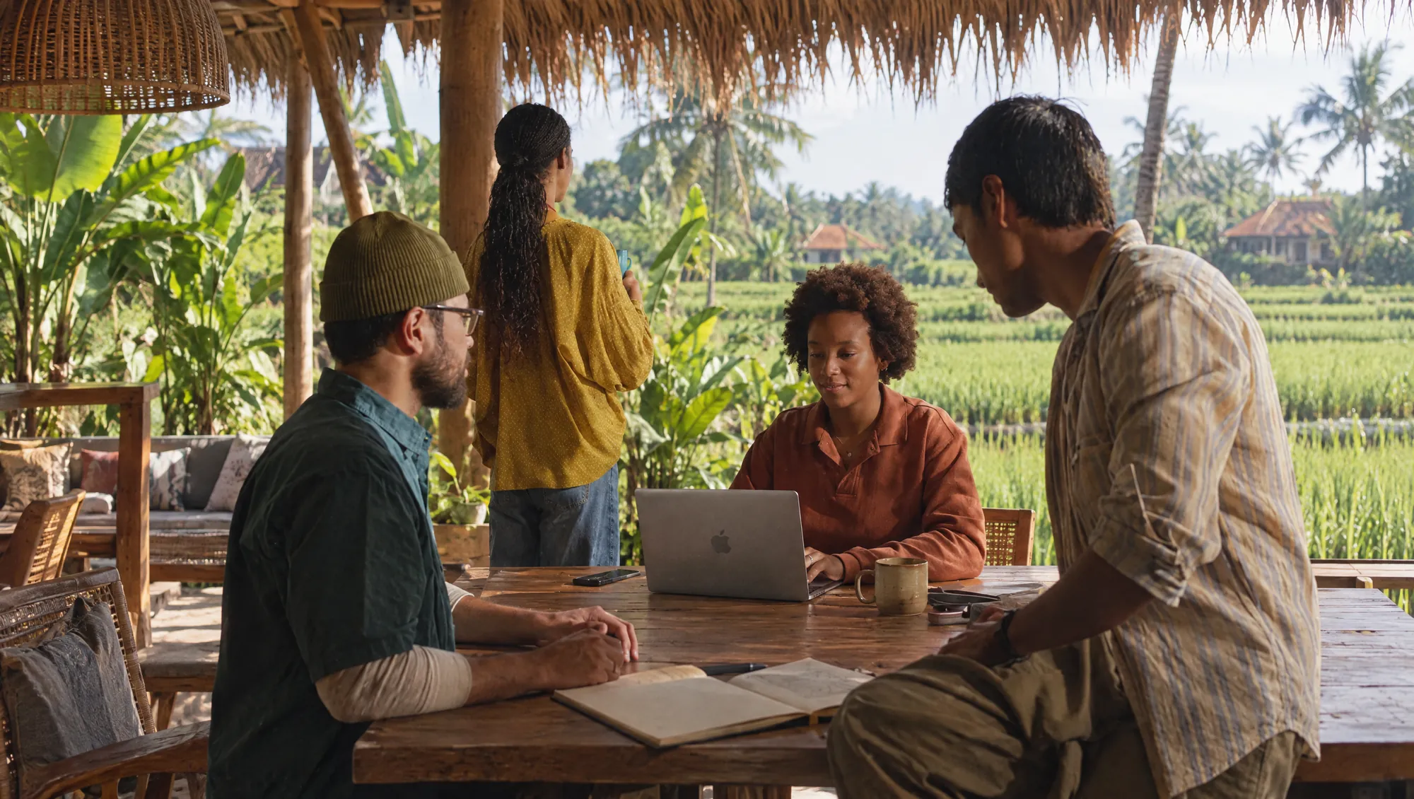 The BEDA team working together at a teak table in an open-air coworking space overlooking rice fields in Bali