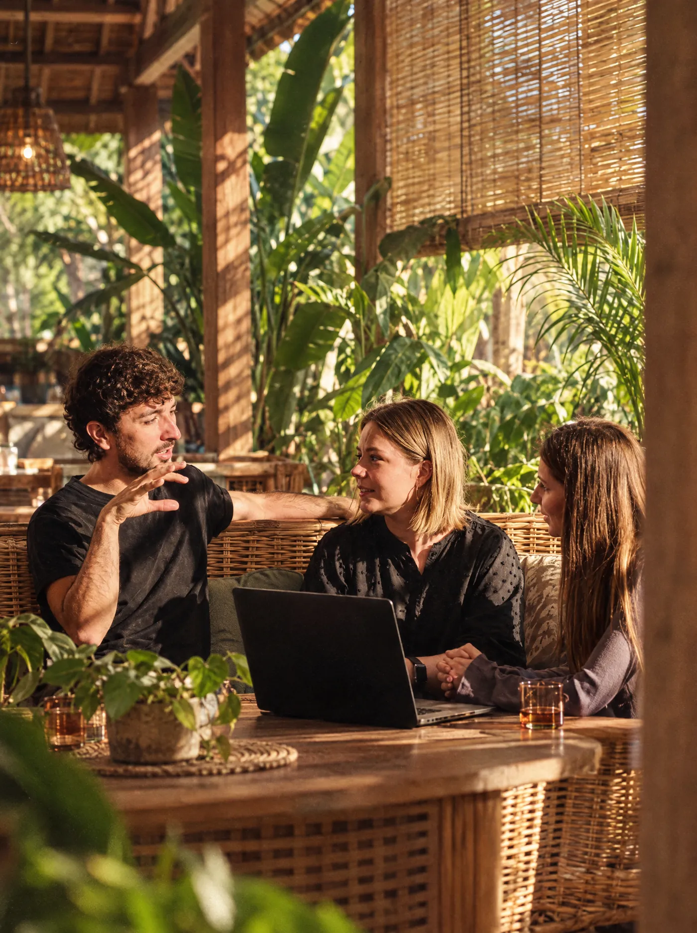 Three reps reviewing a call together around a laptop in a Bali coworking lounge